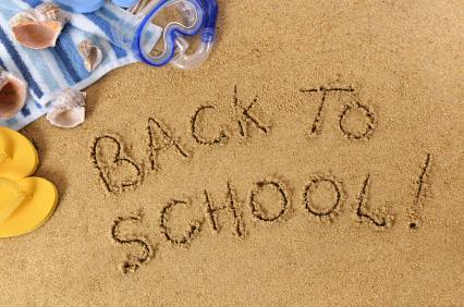 Back To School written on a beach with towel, seashells and flip flops (studio shot - directional light and warm color are intentional).