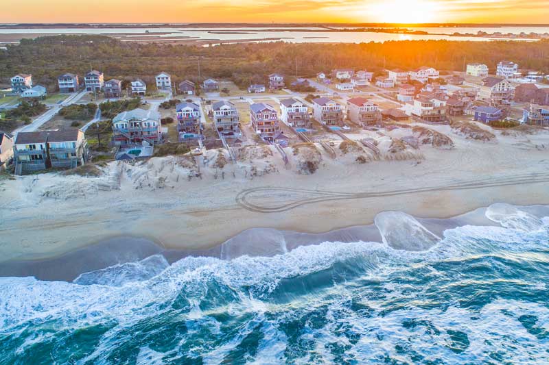 Aerial photo of the ocean and soundside at sunset on the Outer Banks. 