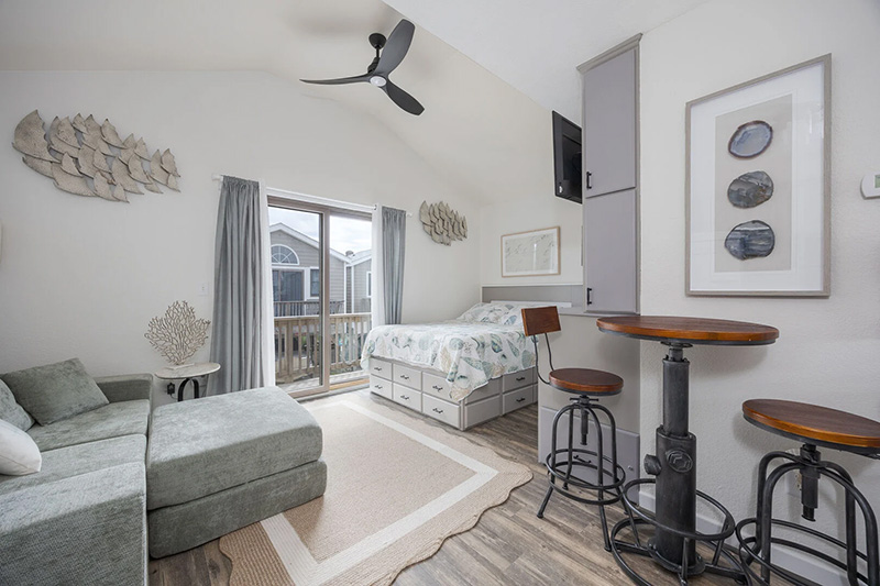 Coastal Outer Banks vacation rental with a bed, sofa, breakfast bar, and beach-inspired decor